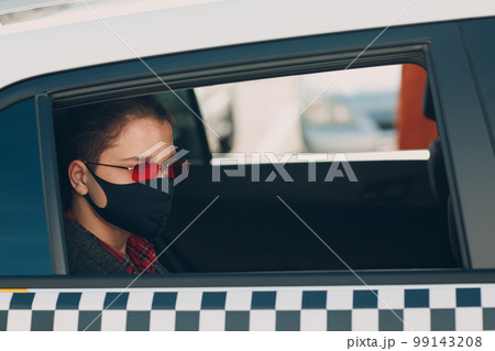 Man passenger in protective face medical mask in the taxi car during an epidemic quarantine city. Health protection, safety and pandemic Covid-19 Man passenger in protective face medical mask in the taxi car during an epidemic quarantine city. Health protection, safety and pandemic Covid-19 99143208