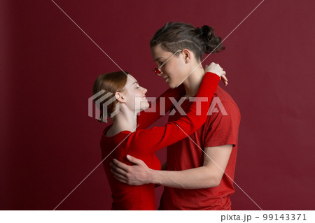 Beautiful young smiling couple hugging on red background. Valentines day concept. 99143371