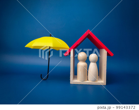 Yellow umbrella protect wooden house and peg doll on a blue background. Planning, saving families, preventing risks and crises, health care and insurance concepts 99143372