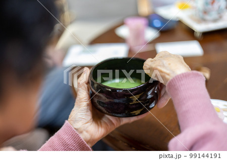 自分の家の食卓でお薄（お抹茶）を点てて飲んでいる高齢女性の手元 99144191