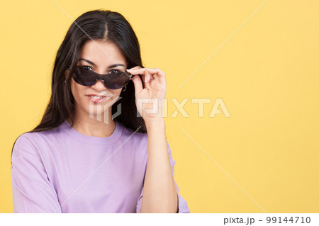 Woman lowering her sunglasses to look at the camera Woman lowering her sunglasses to look at the camera 99144710