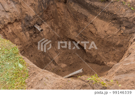 Large deep pit in the ground after digging an excavator sewer pipe in an industrial area Large deep pit in the ground after digging an excavator sewer pipe in an industrial area 99146339