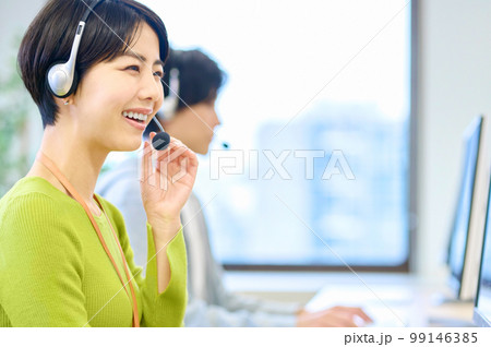 オフィスでヘッドセットをつけて対応するオペレーターの女性 オフィスでヘッドセットをつけて対応するオペレーターの女性 99146385