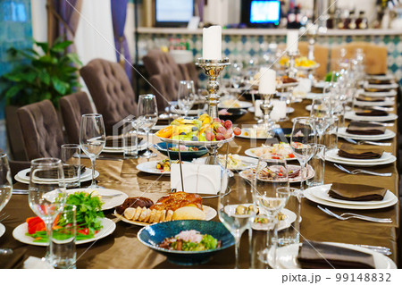 a large festive table with candles, snacks and tableware. 99148832