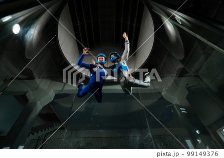 A man teaches a boy to fly in a wind tunnel. 99149376