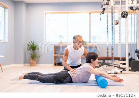 スポーツジムでトレーニングするミドルの女性とトレーナー 99151127