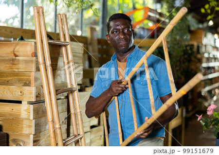 African American looking for decorative bamboo stepladder in gardening shop African American looking for decorative bamboo stepladder in gardening shop 99151679