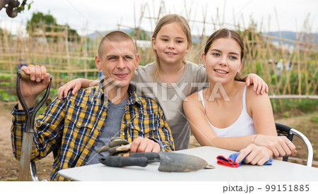 Young family resting after gardening at allotment 99151885