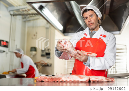 Male seller demonstration quality porks in butcher shop 99152002