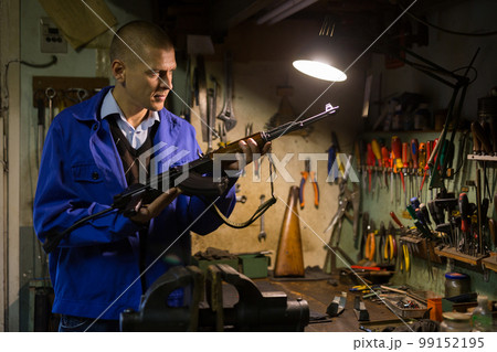 Craftsman of weapons workshop inspecting Kalashnikov assault rifle Craftsman of weapons workshop inspecting Kalashnikov assault rifle 99152195