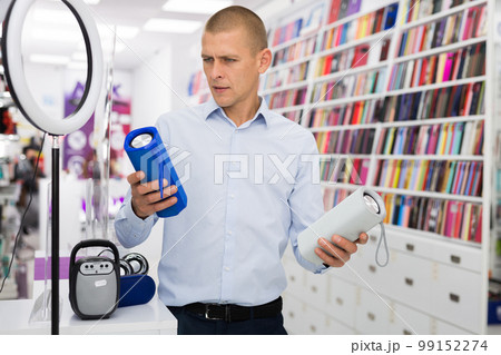 Male customer choosing boombox in consumer electronics store 99152274