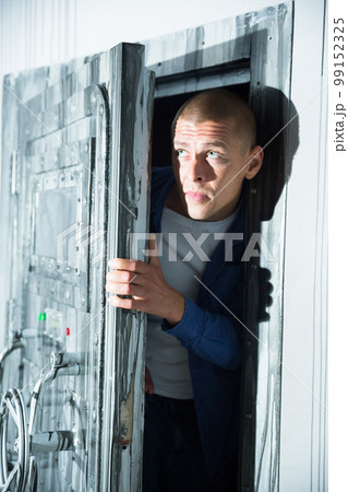 Young man tries to open the door to the quest room, stylized as a secret hideout 99152325