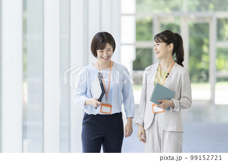 話をしながら歩く2人のビジネスウーマン 話をしながら歩く2人のビジネスウーマン 99152721