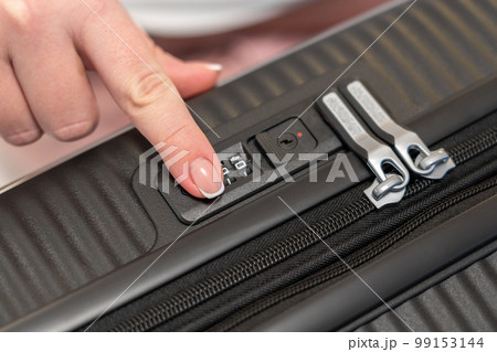 Fingering the numbers on the combination lock of the suitcase to open it 99153144