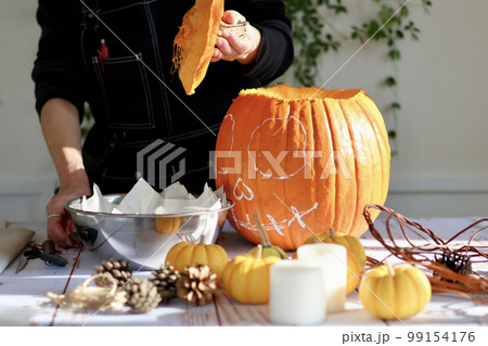 エプロン姿の女性が作るハロウィンのジャックオーランタン　ハロウィンのランタンの作り方 99154176