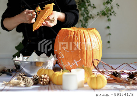 エプロン姿の女性が作るハロウィンのジャックオーランタン　ハロウィンのランタンの作り方 99154178