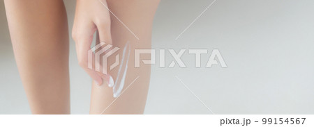 Beautiful young asian woman applying cream or lotion on skin legs with moisturizer on bed. 99154567
