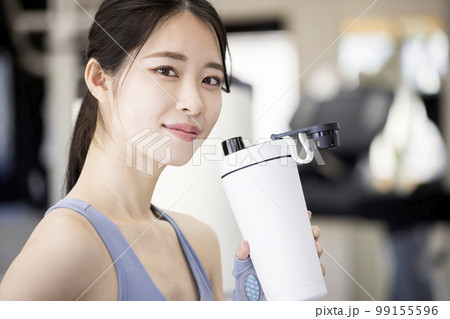 スポーツジムでトレーニング後プロテインを飲む若い女性 99155596