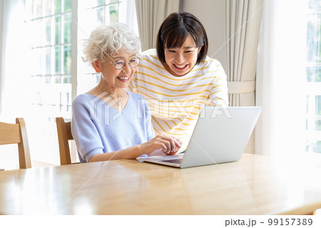 リビングでパソコンを教わるシニア女性 99157389
