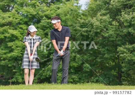 ゴルフ場でゴルフレッスンするゴルファーの男女（ラウンドレッスン） 99157782