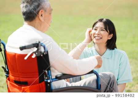 笑顔で働く介護士・車椅子の男性と会話する女性介護士 99158402