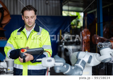 man engineer using remote robot controller operate standing at automation robot arms machine. man engineer using remote robot controller operate standing at automation robot arms machine. 99158634