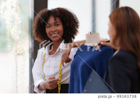 Portrait of young african american woman fashion designer stylish and friend working at fashion studio. 99163738