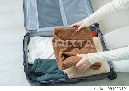 Woman hand packing her winter clothes in luggage. Time to travel, trip, Relax, spring or autumn or winter season and vacation concepts Woman hand packing her winter clothes in luggage. Time to travel, trip, Relax, spring or autumn or winter season and vacation concepts 99165359