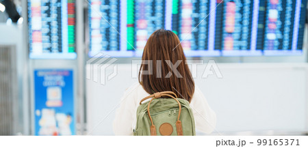 Young woman with backpack looking at the flight time information board in international airport, before check in. Travel, Vacation, trip and Transport concept Young woman with backpack looking at the flight time information board in international airport, before check in. Travel, Vacation, trip and Transport concept 99165371