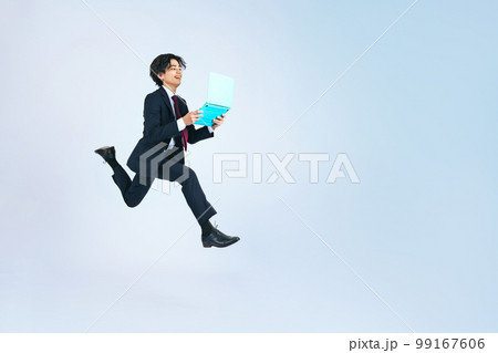 パソコンを持ってジャンプする若いビジネスマン 99167606