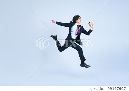 コーヒーカップを持ってジャンプする若いビジネスマン 99167607