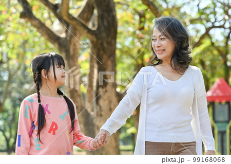 Happy middle aged woman and little granddaughter enjoying leisure weekend tine at outdoor Happy middle aged woman and little granddaughter enjoying leisure weekend tine at outdoor 99168068