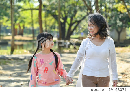 Loving middle aged woman and little granddaughter enjoying leisure weekend time at outdoor surrounded by nature view Loving middle aged woman and little granddaughter enjoying leisure weekend time at outdoor surrounded by nature view 99168071