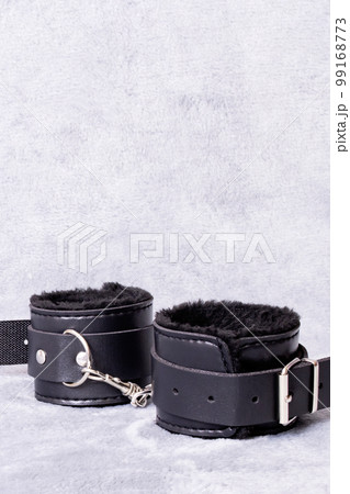 Black leather handcuffs on a gray background 99168773