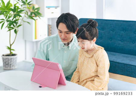リビングでタブレットを見る少女と男性 リビングでタブレットを見る少女と男性 99169233