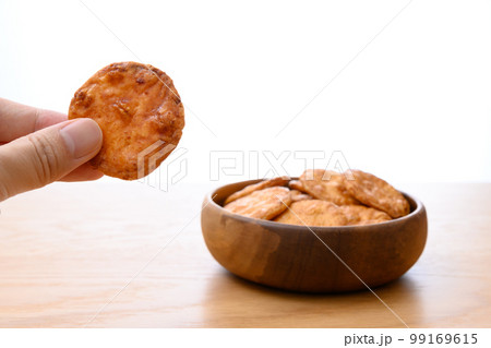 焼きせんべいを持つ手　木の器に入った煎餅　昔ながらのお菓子 99169615