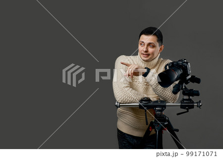 photographer in sweater near digital camera on tripod 99171071
