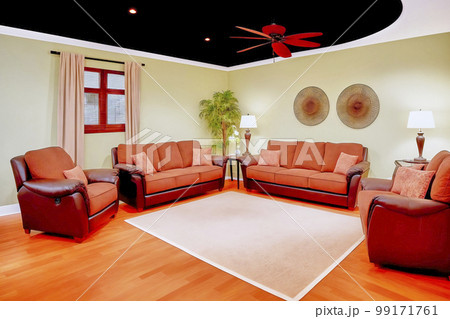 Artificial living area with armchairs, couch and carpet under a fan on the black ceiling, made with generative AI 99171761