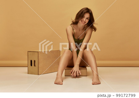 Portrait of young slim beautiful girl wearing green color underwear posing over brown background. Concept of beauty, body and skin care, healthy eating Portrait of young slim beautiful girl wearing green color underwear posing over brown background. Concept of beauty, body and skin care, healthy eating 99172799