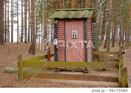 Professionally, qualitatively built wooden toilet in nature. Communal building for tourists in the forest. A fence of wooden planks surrounds the building 99175060