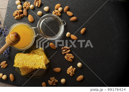 Honeycomb on slate tray with honey and nuts on kitchen table Honeycomb on slate tray with honey and nuts on kitchen table 99176424
