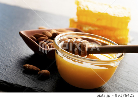 Slate tray with honey almonds and honeycomb on kitchen table 99176425