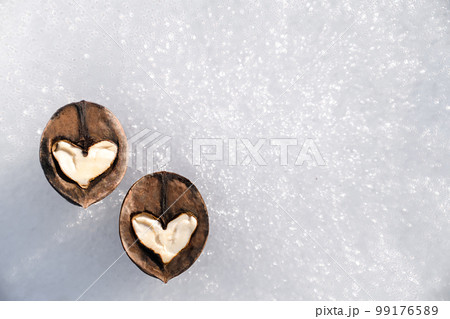 Two white hearts made of walnut halves against background of white snow, concept of love and health, copy space 99176589