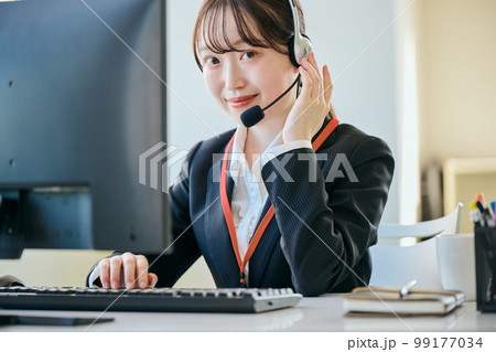 オフィスで電話対応をするカメラ目線の若い女性 オフィスで電話対応をするカメラ目線の若い女性 99177034