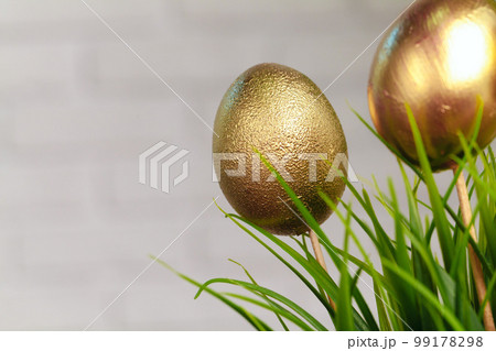 Golden colored Easter eggs stuck to artificial grass 99178298