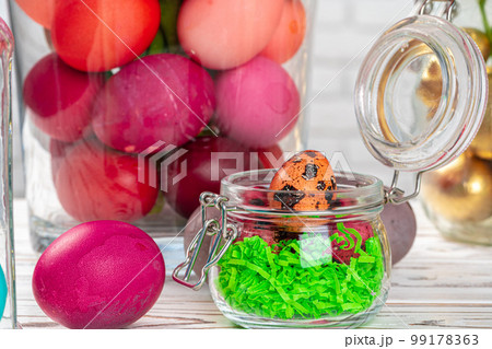 Glass jar with bright colored eggs for Easter celebration 99178363