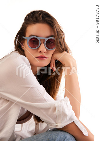 Portrait of young beautiful woman in stylish clothes and trendy sunglasses posing against white studio background. Concept of beauty and fashion 99178753