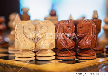 Vintage carved wooden chess pieces on a chessboard on a table indoors. Vintage carved wooden chess pieces on a chessboard on a table indoors. 99181525
