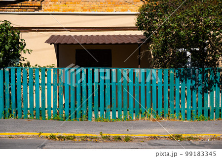 The old weathered wooden green fence near residential homes. The old weathered wooden green fence near residential homes. 99183345