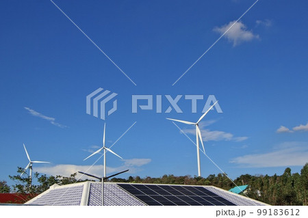 Solar panels on the roof and there are also wind turbines around. The concept of renewable and sustainable resources. Solar panels on the roof and there are also wind turbines around. The concept of renewable and sustainable resources. 99183612